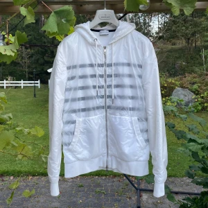 Moncler Cardigan/Windbreaker - Moncler Cardigan/Windbreaker i vit.  Perfekt nu till hösten som en vindtät och vattentät cardigan som håller värmen bra.  Skick 10-10 (som ny). Stl M. Retail 12-15.000kr mitt pris 6.999kr. Säljs pga passar ej mig i stl längre.
