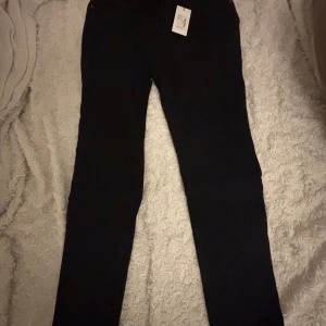 Svarta jeans från 157 i storlek L - Svarta jeans från 157 med klassisk femficksdesign och smal passform. Jeansen har normal midja och raka ben, perfekta för en clean och stilren look. Materialet är jeans och färgen är helsvart, vilket gör dem enkla att matcha med allt.