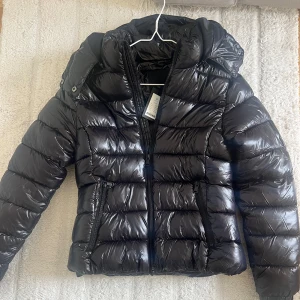 Svart pufferjacka - Säljer en svart, glansig och trendig pufferjacka i storlek S. Nyskick med prislappen kvar. 💗