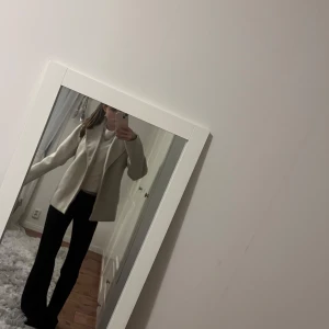 Beige kappa från Vero Moda - Stilren beige kappa från Vero Moda med klassisk krage och knytskärp i midjan. Jackan har lång ärm, rak passform och är tillverkad i ett mjukt ullblandat material. Perfekt för dig som gillar en clean och enkel look. Tveka inte att höra av dig om du har frågor😇