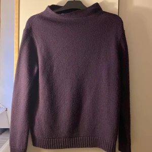 Vinröd/ mörklila stickad tröja från Nelly - Säljer en vinröd/ mörklila stickad tröja från Nelly, modell 5 inch and up. Tröjan har en rak passform, ribbade muddar och en liten krage vid halsen. Perfekt för lager-på-lager och passar till både jeans och kjol.