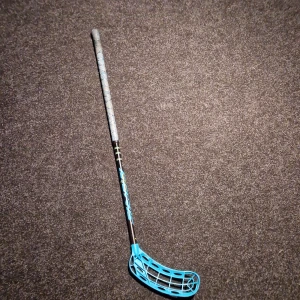 Fat Pipe G27 Floorball Stick - Fat Pipe G27 innebandyklubba med blått blad och svart/blått skaft. Greppet ser fräscht ut och bladet är i gott skick utan synliga sprickor eller större slitage. Perfekt för både träning och matchspel. Lätt och välbalanserad klubba för optimal bollkontroll.