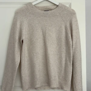 Beige stickad tröja från Vero Moda - Mysig beige stickad tröja från Vero Moda med rund halsringning och ribbade muddar. Perfekt för lager-på-lager och enkel att matcha med jeans eller kjol. Långärmad och i klassisk, stilren modell.
