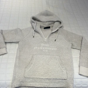 Ljusgrå fleecehoodie Peak Performance - Mysig ljusgrå hoodie från Peak Performance i fleece med broderad logga på bröstet