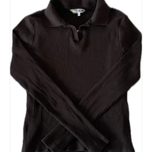 Brun ribbad pikétröja från ONLY - Säljer en brun ribbad pikétröja från ONLY med klassisk krage och lång ärm. Tröjan har en tight passform och är tillverkad i mjukt material som sitter snyggt på kroppen. Perfekt för dig som gillar stilrena och trendiga basplagg.