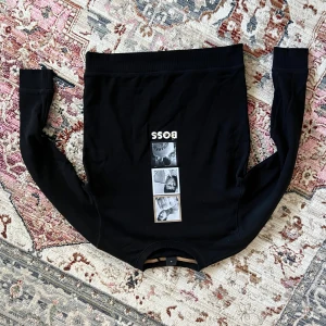 Svart långärmad tröja från BOSS - Svart långärmad tröja från BOSS med tryck av fotoremsor och logga framtill. Mjuk bomullskänsla och ribbade muddar vid ärmslut och nederkant. Snygg detalj med BOSS-tryck även på ryggen. Perfekt till jeans eller dressade byxor. Köpt för 1999kr