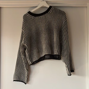 Randig stickad tröja från Divided - Svart och vit randig stickad tröja från Divided. Tröjan har en loose passform, rund halsringning och långa ärmar. Perfekt för lager-på-lager och chill dagar. Snygg kontrast mellan de svarta och vita ränderna, och ribbade kanter vid hals, ärmslut och nederkant.