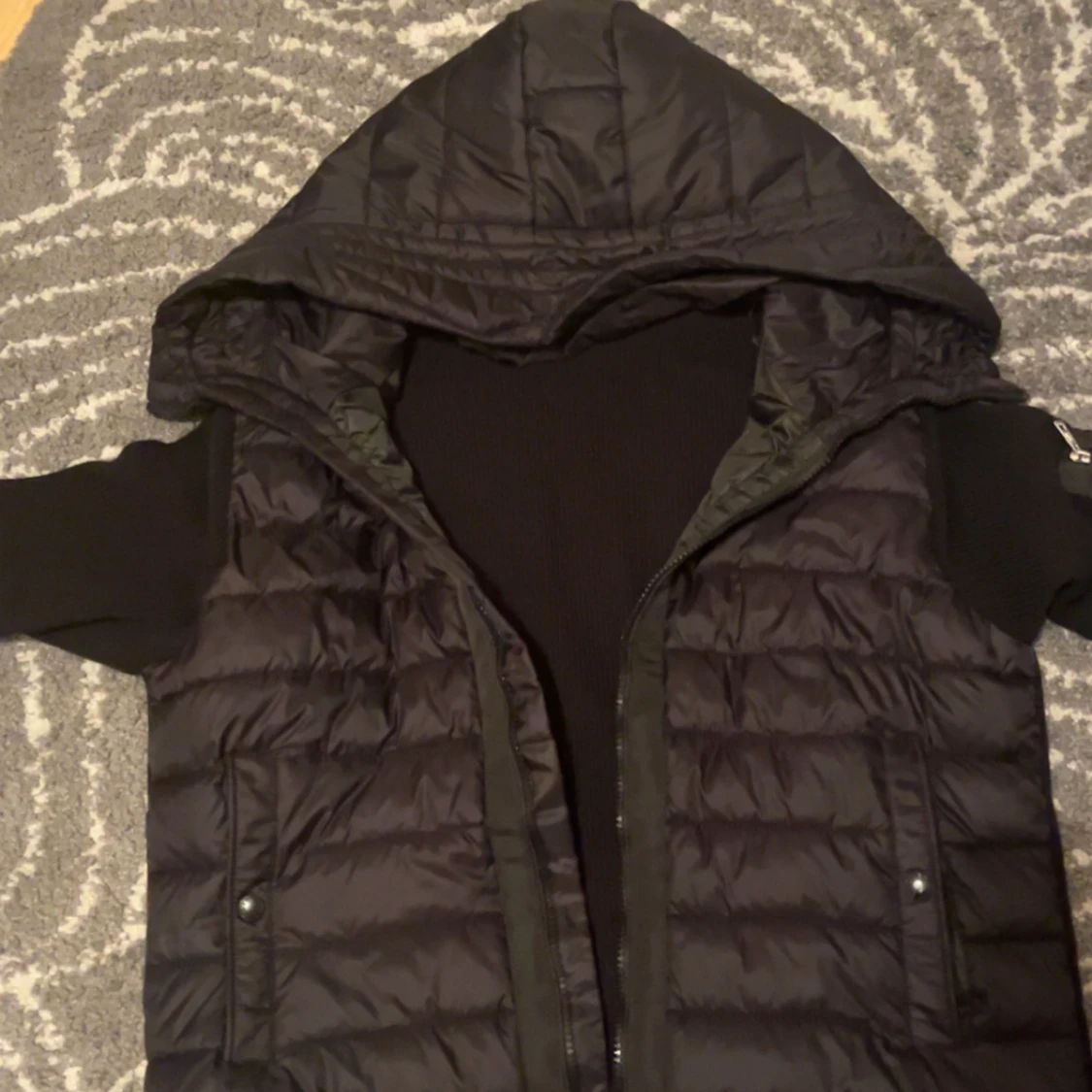 Svart dunväst med huva och stickade ärmar