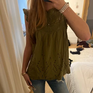 Olivgrön blus med broderade detaljer - Fin olivgrön blus med broderade och hålade detaljer nertill samt spets och volang vid axlarna.  Perfekt färg till hösten 🍂💗