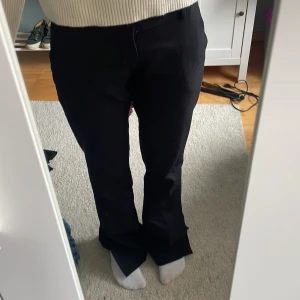 Svarta kostym byxor - Säljer ett par svarta byxor med bootcut-snitt och normal passform. Byxorna har klassisk design med fickor och bälteshällor, perfekta för en clean och stilren look. Materialet känns mjukt och följsamt, passar dig som gillar enkel men snygg stil. Byxorna är lågmidjade.