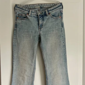 Ljusblå bootcut jeans från Monki - Säljer ett par ljusblå jeans från Monki med bootcut-modell och klassisk femficksdesign. Jeansen har en snygg tvättad look och är tillverkade i jeansmaterial med normal passform upptill och utsvängda ben. Stl 24/32