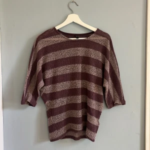 Lilarosa stickad tröja  - Kortärmad stickad lilarosa tröja. Randig. Ganska tunn. Storlek S. Gott skick.