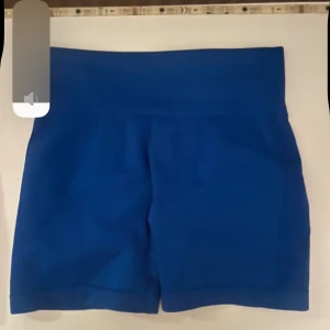 Två par träningstights shorts - Säljer två par sömlösa shorts i stretchigt material, ett par i klarblått och ett par i stark rosa. Båda har hög midja och tight passform, perfekta för gym eller träning. Båda har scrunch-detalj bak för extra shaping. Supersköna och trendiga för gymmet