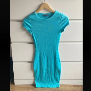 Turkos tight kortklänning - Enkel och snygg turkos kortklänning från Bershka med tight passform och korta ärmar. Klänningen är ribbad och har rund halsringning, perfekt för dig som gillar en stilren look med färg. Även sportig. 