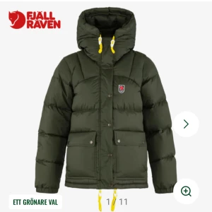 Grön dunjacka från Fjällräven - Snygg mörkgrön dunjacka från Fjällräven med huva och gula snören. Jackan har två stora fickor framtill, dragkedja och knappar samt klassisk Fjällräven-logga på bröstet. Perfekt för kalla dagar och riktigt skön passform. Endast använda fåtalgånger nypris 7499