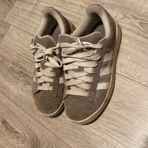 Gråa Adidas campus 00’s - Hej, jag säljer mina adidas campus pga att dem är för små och inte kommit till andvändning. Skorna i sig är i andvänt skick men inga större defekter. Hör av dig vid funderingar om pris m.m.