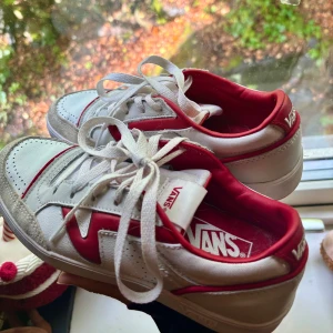 Vans Lowland sneakers - Säljer ett par Vans Lowland sneakers i vitt och rött med röd V-logga på sidan. Skorna har ovandel i skinn och mocka. Röd insida och detaljer ger en snygg kontrast till den vita basen. Perfekta för en streetwear-look tycker jag 🥰 burna totalt noll gånger då de var alldeles för stora för mig, skriv gärna vid frågor! Nypris var ca 600kr