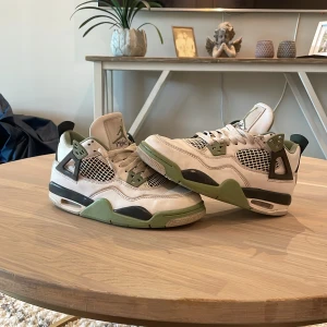 Nike Air Jordan 4 Retro vit/grön - Nike Air Jordan 4 Retro sneakers i vitt och olivgrönt med svarta detaljer. Skorna har meshpaneler, snörning och den klassiska Jumpman-loggan på plösen och hälen. Ovandelen är i skinn och mesh, med gröna och svarta accenter på sula och detaljer. Har tyvärr inte boxen. ny pris ungefär 3999kr mitt pris 749🏆 
