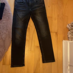 Svarta Detroit jeans från Lindex, strl 134 - Svarta jeans från Lindex Detroit med snygga slitningar och smal passform. Klassisk femficksmodell med raka ben och cool tvätt. Perfekta för dig som gillar en stilren look med lite edge.