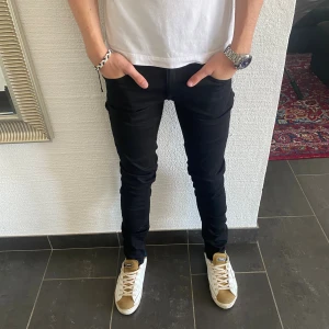 Tiger of Sweden Jeans - Svarta slim fit jeans med snygg, smal passform. Klassisk femficksmodell i stretchigt material som sitter tajt längs benen. Tillverkade i Italien och perfekta för dig som gillar en stilren och modern look.