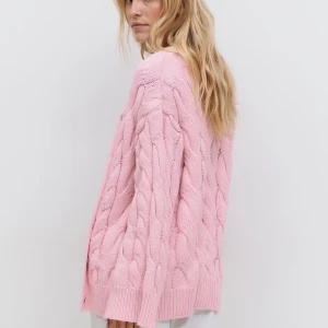 Rosa kabelstickad kofta från Gina Tricot - Superfin rosa kofta från Gina Tricot med kabelstickat mönster och pärlemorknappar framtill. Koftan har en loose fit, ribbade muddar och är långärmad. Perfekt för lager-på-lager och ger en söt vibe till din outfit. Knappt använd och helt slutsåld, kommer ej in i lager igen.