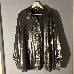Silver skjorta  - Lightweight silver skjorta. Storlek S. Bara använd en gång så inga defekter eller missfärgningar. (Den ser glittrig ut på bilderna men den är bara glansig).
