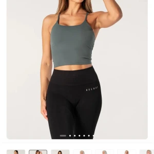 Grågrön croppad linnetopp från reload  - Snygg croppad linnetopp i grågrön färg med tunna axelband och rak halsringning. Perfekt för träning eller chill dagar. Toppens material är stretchigt och följsamt för maximal komfort.