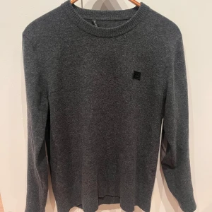 Mörkgrå stickad tröja Acne Studios - Mörkgrå stickad tröja från Acne Studios med rund halsringning och diskret logopatch på bröstet. Tröjan har lång ärm och snygga förstärkta armbågslappar i grått. Skön tröja för hösten och vintern. I perfekt skick utöver taggen på insidan som ni ser på sista bilden. Nypris omkring 3000 kr.