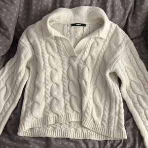 Vit kabelstickad tröja från BikBok - Kabelstickad vit tröja från BikBok i storlek XS. Tröjan har en bred krage med v-ringning och är gjord i en mjuk blandning av polyester, ull och elastan. Perfekt för kyliga dagar och har långa ärmar samt ribbade muddar. Passar även till dem som har S i storlek
