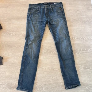 Replay Anbass jeans blå herr 34 - Säljer ett par Replay Anbass jeans i klassisk blå tvätt. Jeansen har raka ben, fem fickor och snygga detaljer vid fickorna. Märket syns tydligt på både knapp och ficka. Perfekta för dig som gillar en stilren och tidlös look.