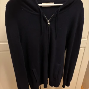 Mörkblå Kashmir hoodie från Sayless - Mörkblå Kashmir hoodie från Sayless med dragkedja framtill och två fickor.  Storlek L men sitter som M! Tröjan har huva med snörning och är långärmad. Perfekt för kyliga dagar och enkel att matcha med jeans eller joggers.
