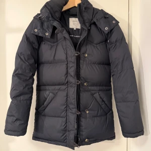 Svart dunjacka från Boomerang XXXS - Säljer en svart dunjacka från boomerang i modellen Alexandra, storlek XXXS. Jackan har huva, dragkedja och knappar framtill, samt två snedställda fickor. Puffad design och snygga detaljer gör den perfekt för kalla dagar. Skriv för frågor och prisförslag!💗