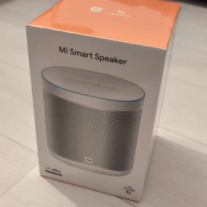 Mi Smart Speaker - Mi Smart Speaker med Google Assistant, kraftfullt ljud, DTS Professional Tuning och Hi-Fi Audio Processor. Styr musik, smarta hem och få svar på frågor. Produkten är fabriksny och oöppnad i originalförpackning. Förpackningen är 25x16 cm.