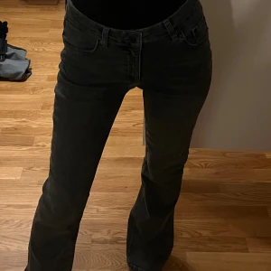 Grå bootcut jeans från Gina Tricot - Snygga grå jeans från Young-Gina Tricot med bootcut passform. Jeansen har klassisk femficksdesign, bälteshällor och svarta detaljer. Materialet är mjukt och stretchigt jeans, perfekt för en trendig look.