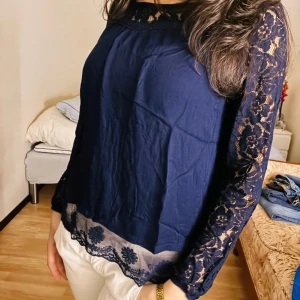 Spets - Mörkblå blus med långa ärmar i spets och transparenta spetsdetaljer vid halsringning och nederkant. Blusen har blommönstrad spets och en lös passform som ger en luftig känsla. Perfekt att styla med jeans eller kjol. Postar redan samma dag eller dagen efter❤️