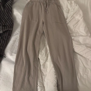 Beige mjukisbyxor med snörning XS - Beiga mjukisbyxor från 157 i storlek XS. Byxorna har resår och snörning i midjan, stora fickor fram och bak samt raka ben. Tillverkade i mjukt bomullsmaterial som är perfekt för chill dagar. Snygg och enkel design som passar till allt.