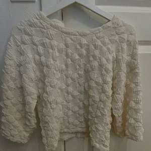Vit quiltad tröja Carin Wester S - Unik vit quiltad tröja från Carin Wester i storlek S. Tröjan har ett coolt texturerat mönster med upphöjda detaljer och rund hals. Långärmad och med en loose passform som ger en chill vibe. Perfekt för dig som gillar statement-plagg och vill sticka ut.