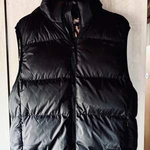 Svart pufferväst från Black Gold! - Svart pufferväst med fickor fram och avtagbar huva från Black Gold i storlek L. Ny och oanvänd.