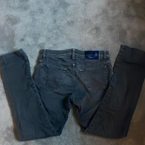 Gråa Jacob cohën jeans - Snygga gråa jeans från Jacob Cohën i klassisk femficksmodell. Jeansen har raka ben, diskreta kontrastsömmar och en stilren look. Tillverkade i mjukt bomullsmaterial med en liten stretch för extra komfort. Perfekta för dig som gillar premiumjeans med italiensk känsla.