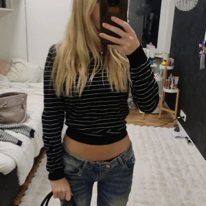 Svart randig tröja från C&A The Basics - Svart långärmad tröja från C&A The Basics i storlek S. Tröjan har vita horisontella ränder och en rundad hals. Passformen är normal och materialet känns mjukt och lätt, perfekt för chill dagar. Snygg att matcha med jeans eller kjol.