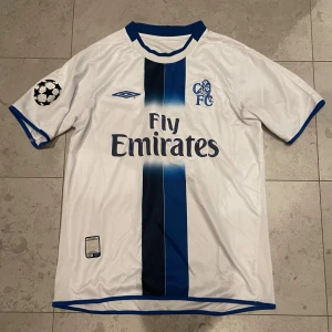 Chelsea 2003/2004 Bortaställ Retro Fotbollströja  - Tja! Säljer nu min galet fina Retro Chelsea tröja, bortastället från 2003/2004, i fint skick. Endast ”Fly Emirates” texten som sitter lite lite löst, annars i bra skick! Storlek: S/M Skick: 7.2/10 Hör gärna av dig vid frågor eller prisförslag, tar bud!🤗