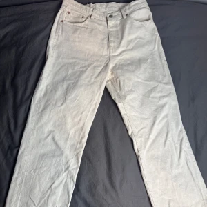 Beige jeansbyxor från Dr Denim 30/32 - Snygga beige jeansbyxor från Dr Denim i klassisk rak/relaxed modell. Byxorna har fem fickor, bälteshällor och dragkedja. Tillverkade i bomull för en skön känsla och stilren look. Perfekta för dig som gillar minimalistisk stil.