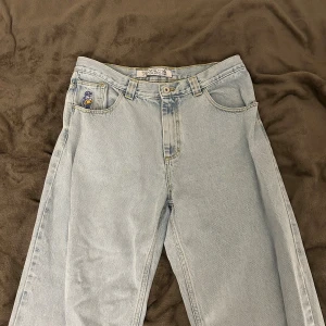 Polar 93 denim jeans  - Ljusblå raka jeans från Denim & Co med cool broderad figur på myntfickan och gul patch bak. Klassisk femficksmodell med bälteshällor och gul kontrastsöm. Perfekta för dig som gillar en avslappnad och retro vibe.