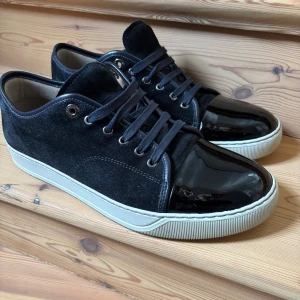 Mörkblåa Lanvin i mocka - Snygga mörkblåa skor från Lanvin med ovandel i mjuk mocka och lackad tå i skinn. Skorna är i ett grymt skick och ser i princip inte använda ut. Storlek 42-43 EU eller UK 8. 2799kr ( nypris 4500), dustbag kommer med. Kan fraktas samma dag med instabox eller postnord. Perfekt för dig som gillar stilrena och exklusiva detaljer. Kontakta mig vid frågor eller funderingar!😁OBS! Inga byten