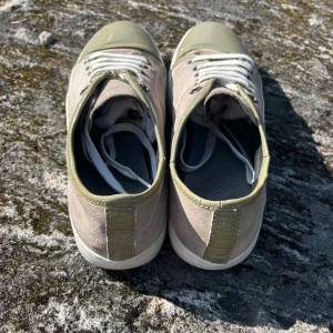 Lanvin sneakers i beige och olivgrön - Snygga sneakers från Lanvin i beige mocka med olivgröna detaljer i lack och vit sula. Skorna har vita snören och rund tå, samt en stilren design som passar till det mesta. Perfekt för dig som gillar exklusiva och unika sneakers med en twist.