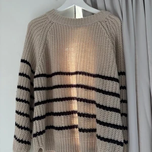Beige stickad randig tröja - En lite chunky stickad tröja i beige med svarta ränder. Tröjan har en avslappnad passform.