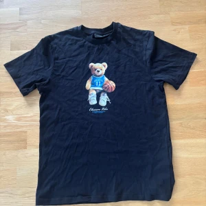Svart t-shirt Closure LDN med nalle - Svart t-shirt från Closure LDN i bomull med tryck av en nallebjörn. Väldigt skön och stilren t-shirt. Går att matcha med allt! Använd ett fåtal gånger (syns på skicket)