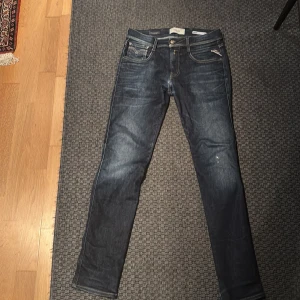 Replay Anbass mörklblå 30/32 - Snygga mörkblå Replay Anbass jeans i slim fit. Jeansen har en stilren look med diskreta slitningar på framsidan, Perfekta för dig som gillar trendiga byxor
