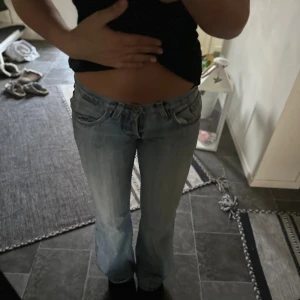 Ljusblå bootcut jeans från Westman - Säljer ett par ljusblå jeans från Westman med bootcut passform och låg midja. Jeansen har klassiska fem fickor, snygga slitningar och detaljerade sömmar på bakfickorna. Perfekta för dig som gillar en avslappnad och trendig look.