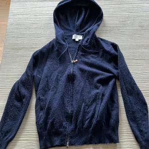 Mörkblå hoodie från Ahlquist Clothing - Mysig mörkblå hoodie från Ahlquist Clothing i storlek XXS. Tröjan har huva, dragkedja framtill och långa ärmar. Perfekt för dig som gillar en enkel och klassisk look. Materialet känns mjukt och passar bra till kyligare dagar. Pris kan diskuteras tar bort allt moppen jag kan till den som köper den